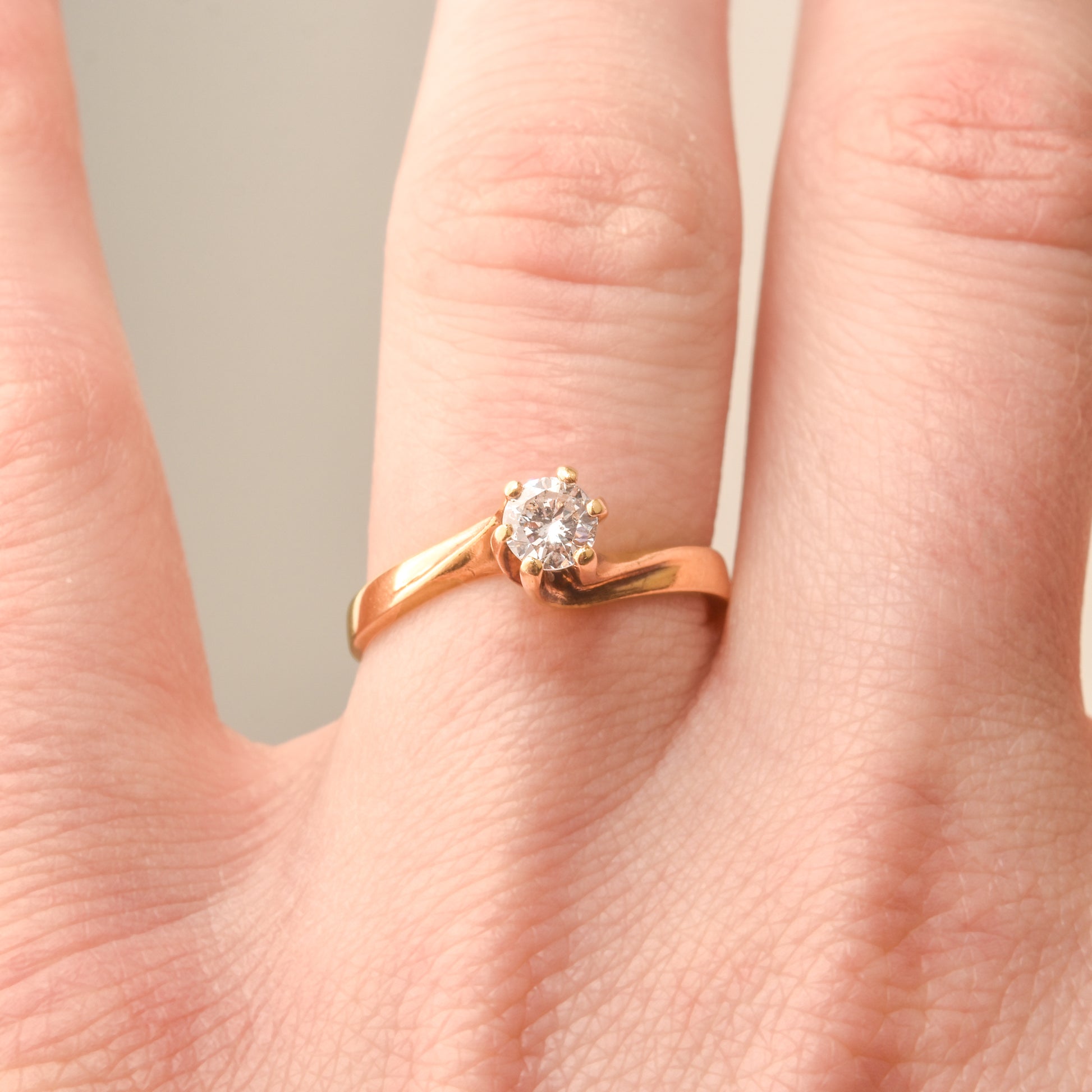 18K yellow gold diamond solitaire engagement ring with 6-prong spiral setting, size 7.5 US, showcased on a finger.