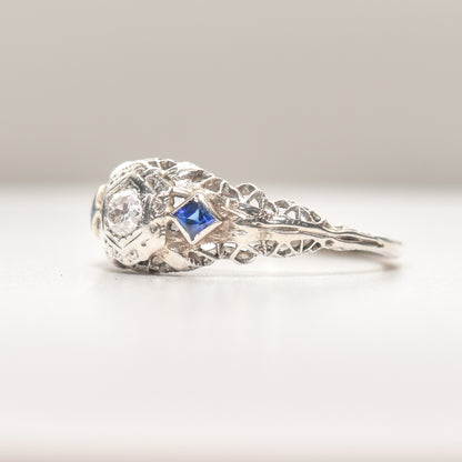 Art Deco 18K white gold engagement ring with diamond and synthetic sapphire filigree design, size 6.25 US, showcased on a neutral background.