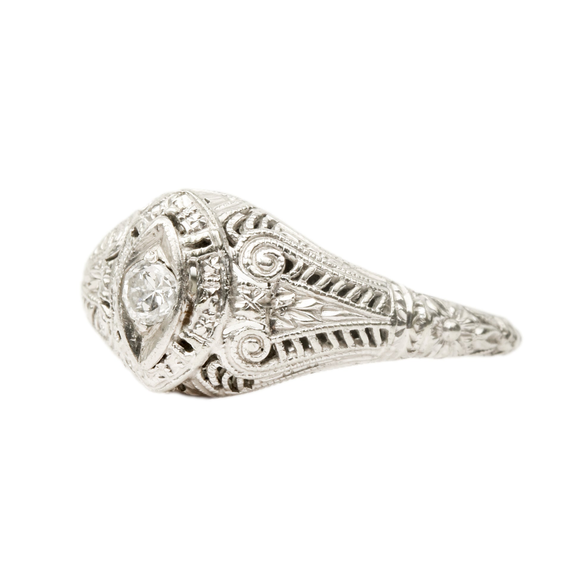 Art Deco 18K white gold filigree diamond solitaire ring featuring a 0.08 carat brilliant diamond, intricate metalwork, size 6.25 US, on a white background.