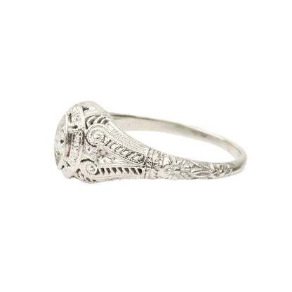 Art Deco 18K white gold filigree diamond solitaire ring with .08 carat brilliant diamond, size 6.25 US, against a white background.