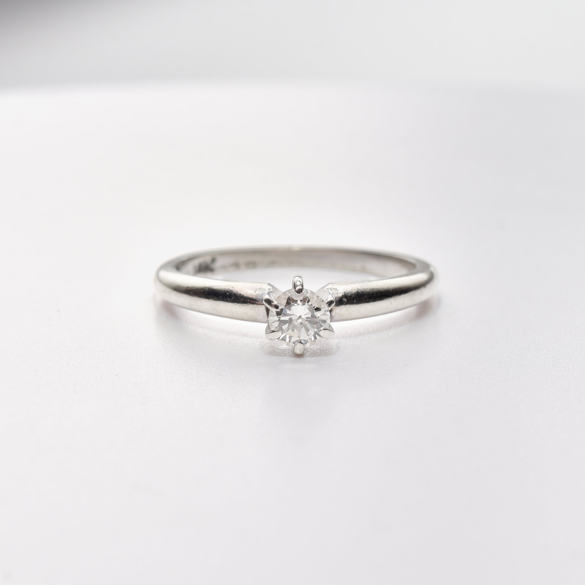 Minimalist 14K white gold diamond engagement ring featuring a .25 carat brilliant solitaire, size 6.25 US, on a white background.