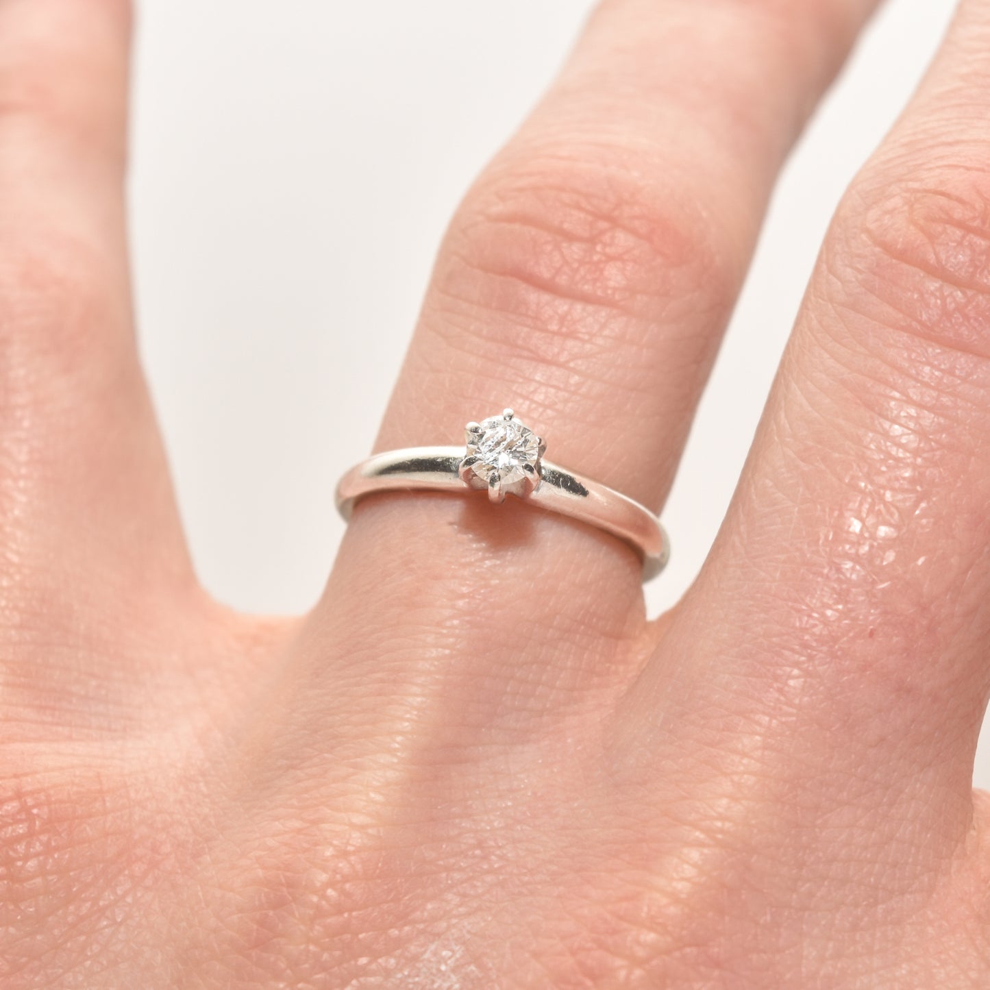 Minimalist 14K white gold engagement ring with 0.25 carat brilliant solitaire diamond on a size 6.25 finger.