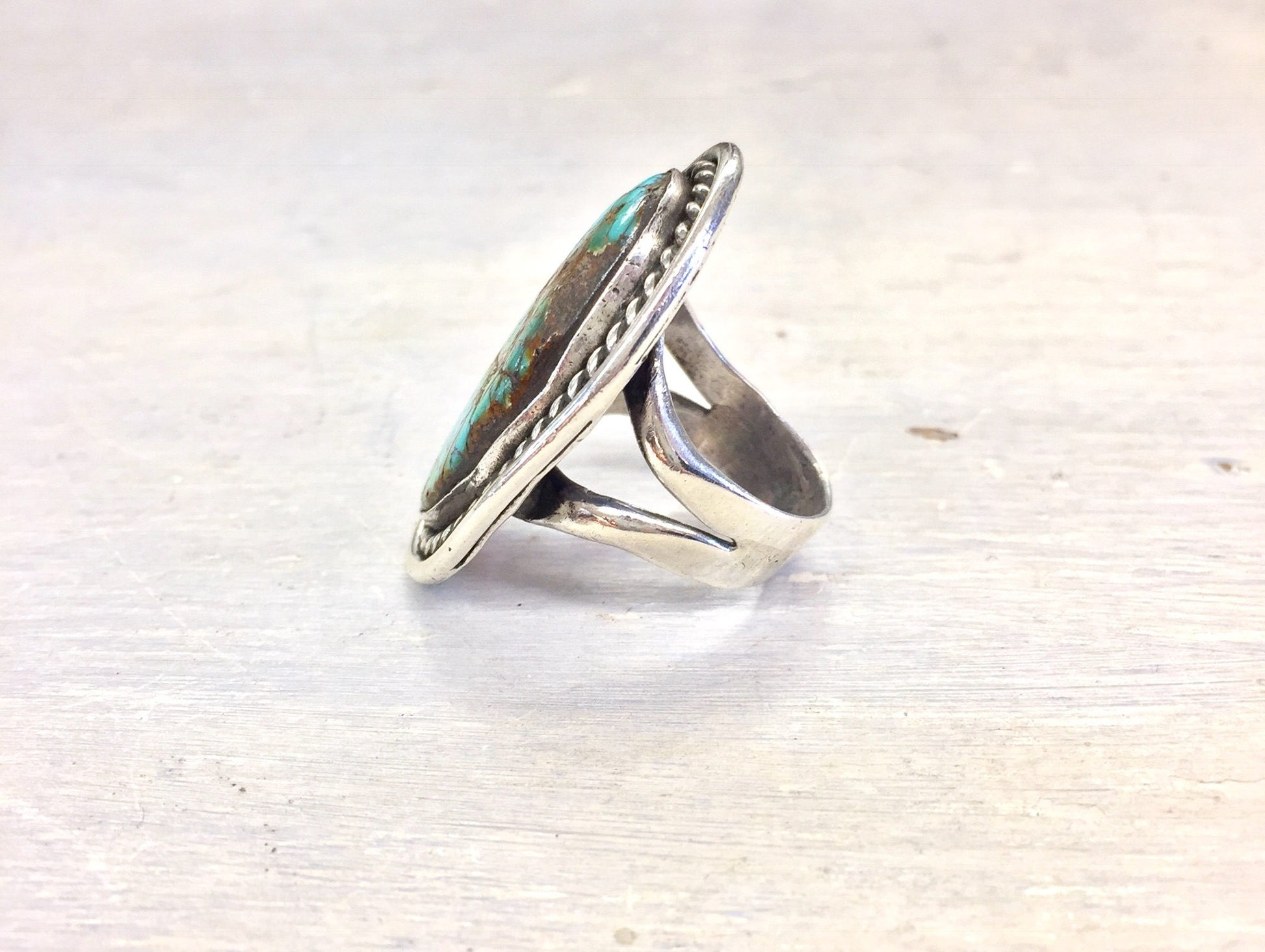 Vintage oversized turquoise stone ring in silver setting against white wooden background