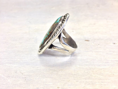 Vintage oversized turquoise stone ring in silver setting against white wooden background