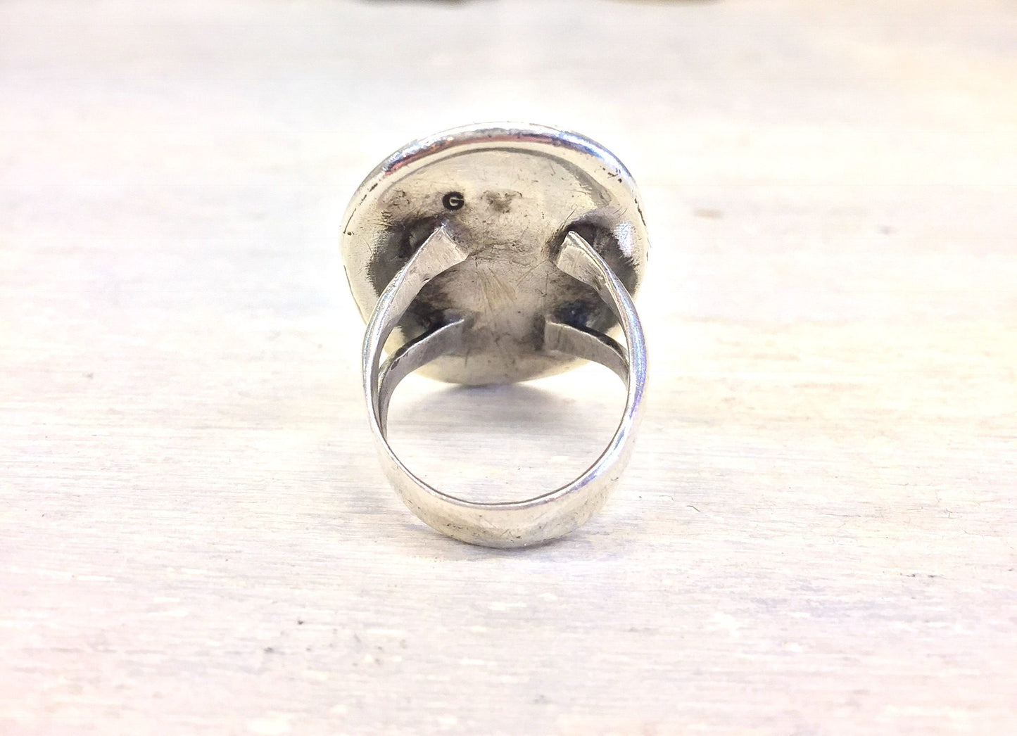 Vintage silver ring with large oval turquoise stone set in ornate scrollwork setting, viewed from the front on a white background.