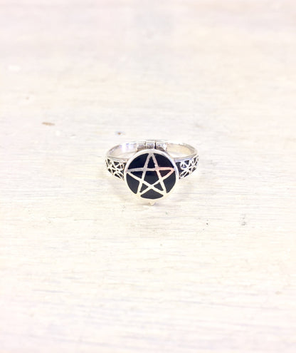 Sterling silver pentagram poison ring against white fabric background