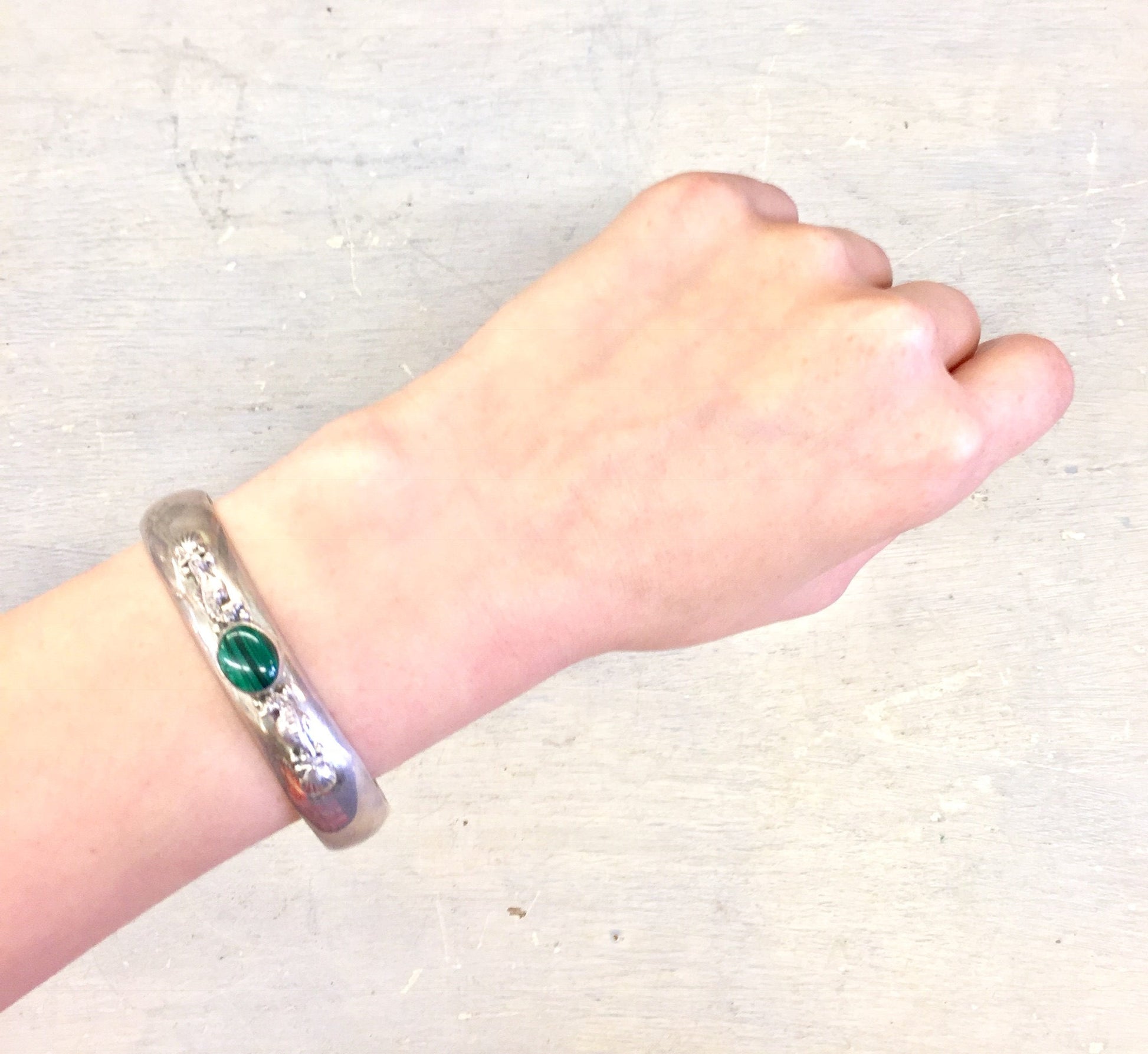 Sterling silver cuff bracelet with malachite stone inlay and seahorse design, shown on a person's wrist against a light background.