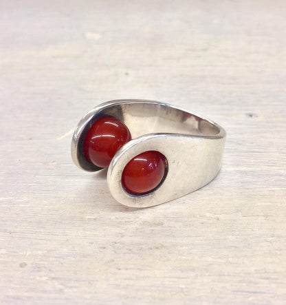 Sterling silver ring with two round carnelian stones set in an open bypass design.