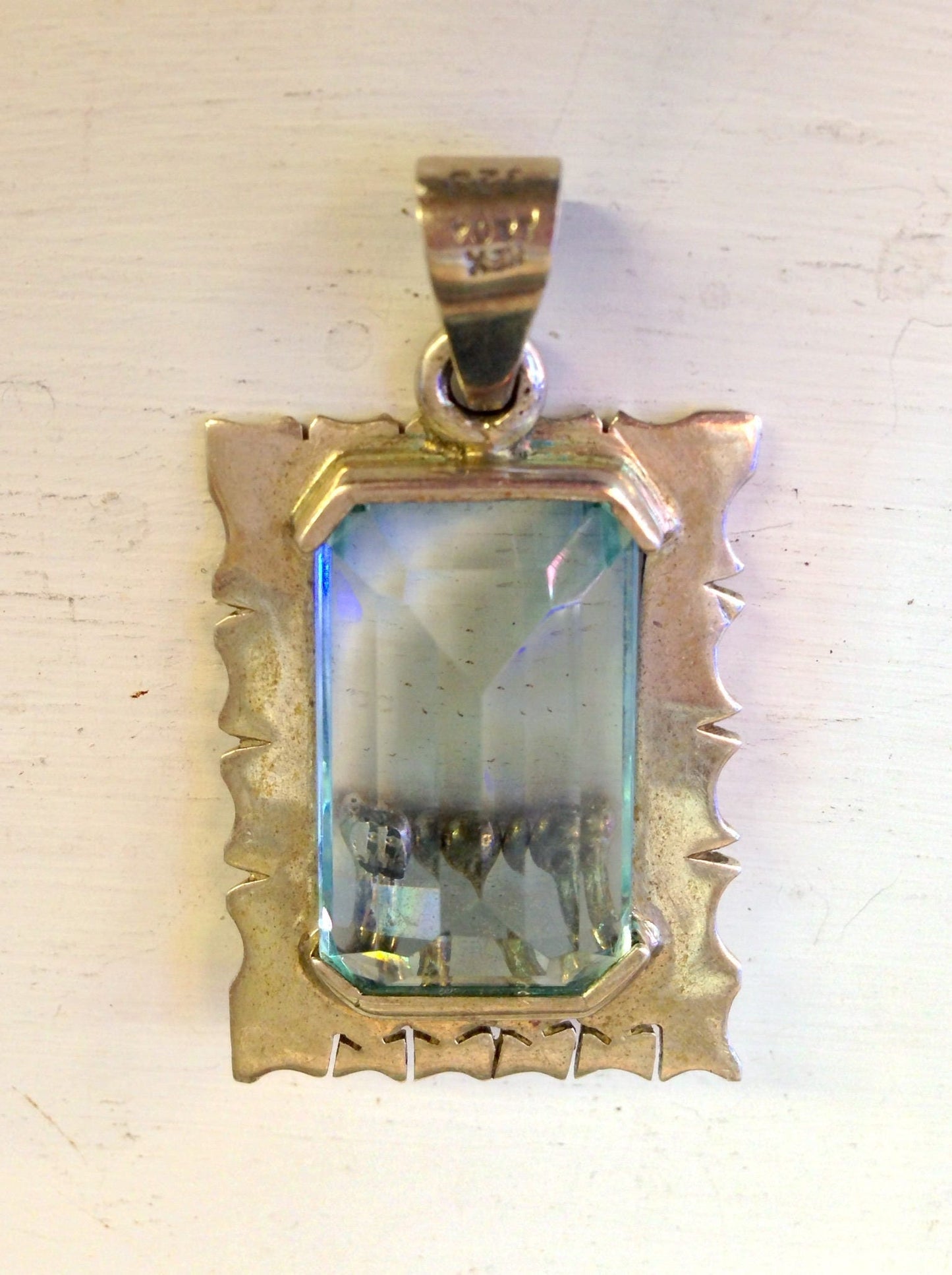 Vintage sterling silver aquamarine pendant with an ornate border, featuring a rectangular faceted aquamarine gemstone in the center.