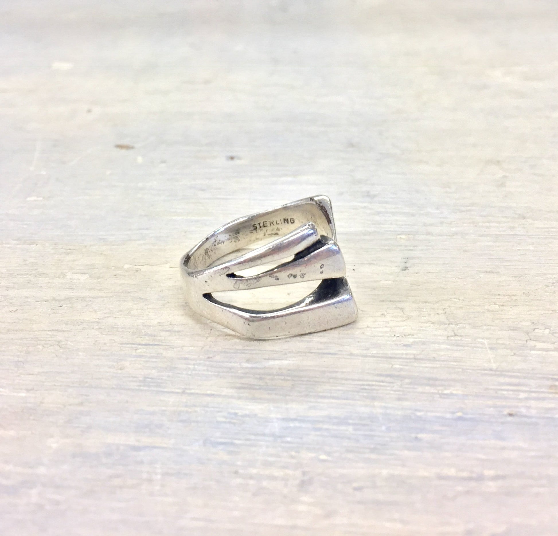 Sterling silver vintage bypass ring on white wooden background