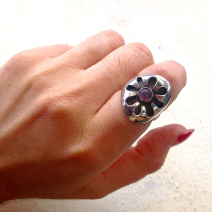 Vintage silver ring with purple amethyst gemstone flower design, worn on finger