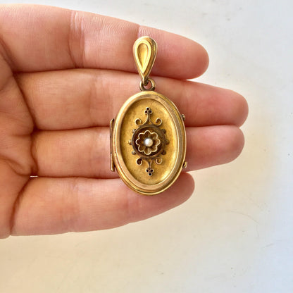 10 karat gold Victorian locket pendant showcasing an intricate floral design, held in a person's hand against a plain background.