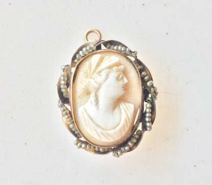 Antique 10 karat gold cameo brooch pendant featuring a detailed carved shell cameo portrait set in an ornate gold frame with pearl accents.