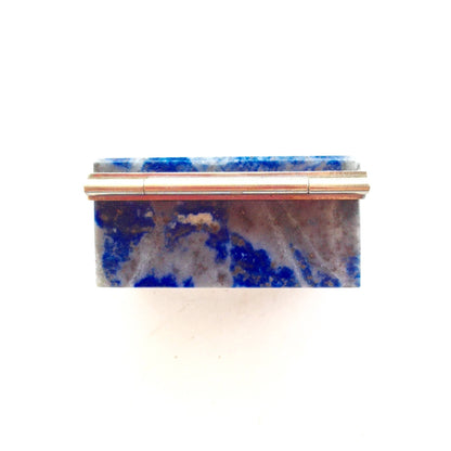 Antique rectangular lapis lazuli stone box with gold trim, containing vibrant blue lapis with white and gray inclusions, against a plain white background.