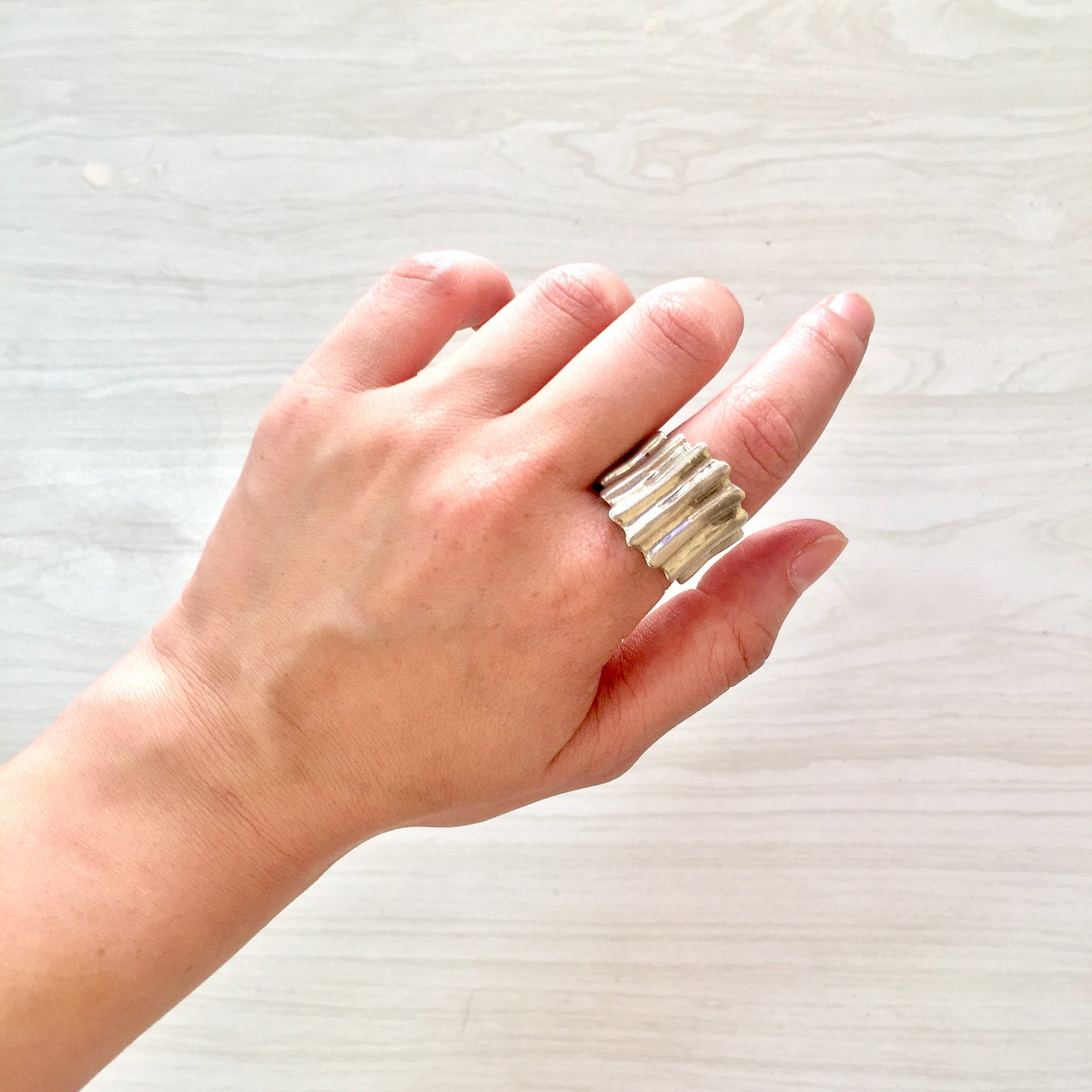 Sterling silver concave ring with textured vintage design held in hand, minimalist unisex jewelry statement piece