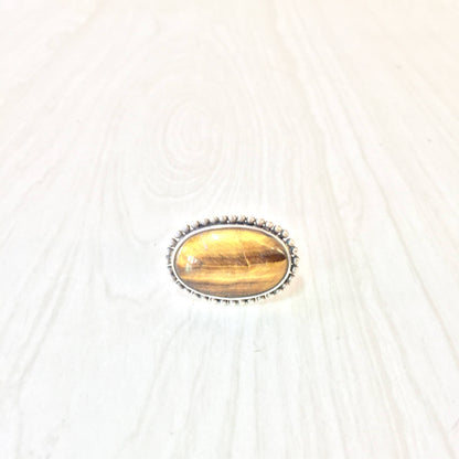 Vintage oval tiger's eye gemstone ring in sterling silver 925 setting, side view on light wood background