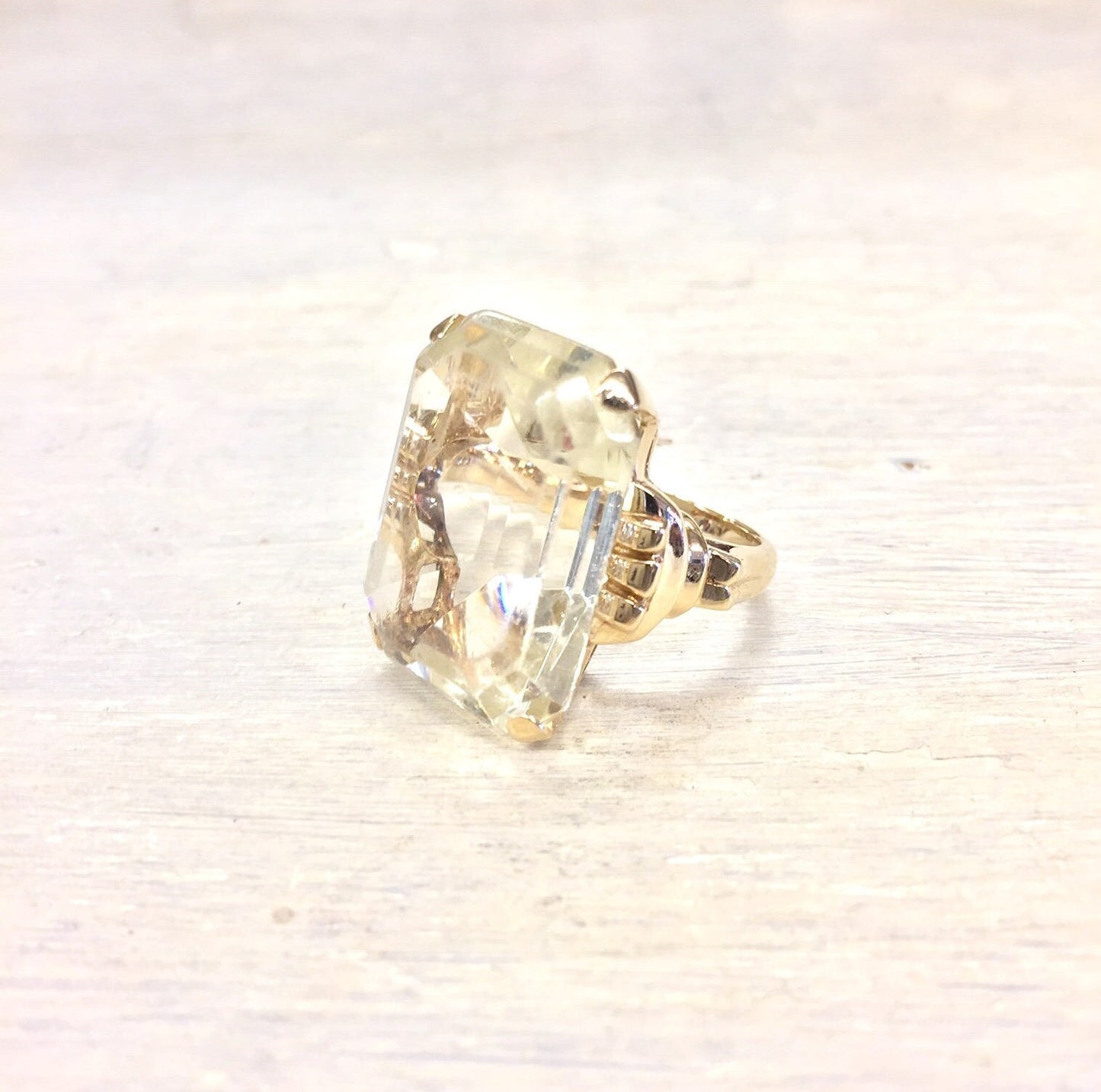 14 karat gold vintage cocktail ring with large rectangular faceted clear gemstone on white background