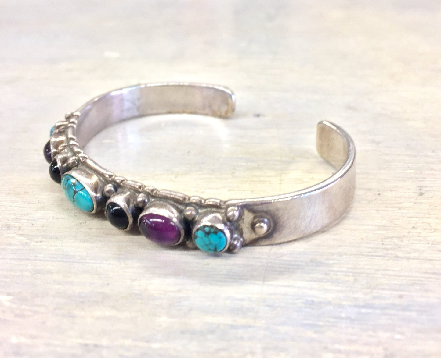 Sterling silver cuff bracelet with turquoise, purple, and black onyx gemstones set in a vintage style design.