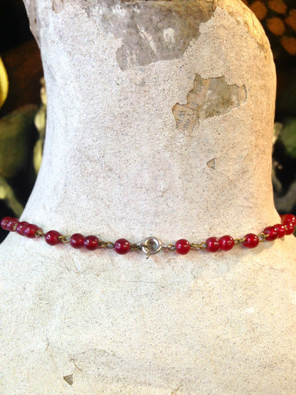 Vintage red beaded necklace on antique stone sculpture, gothic jewelry from the past