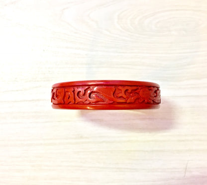 Red cinnabar bangle bracelet with intricate Asian carved dragon design