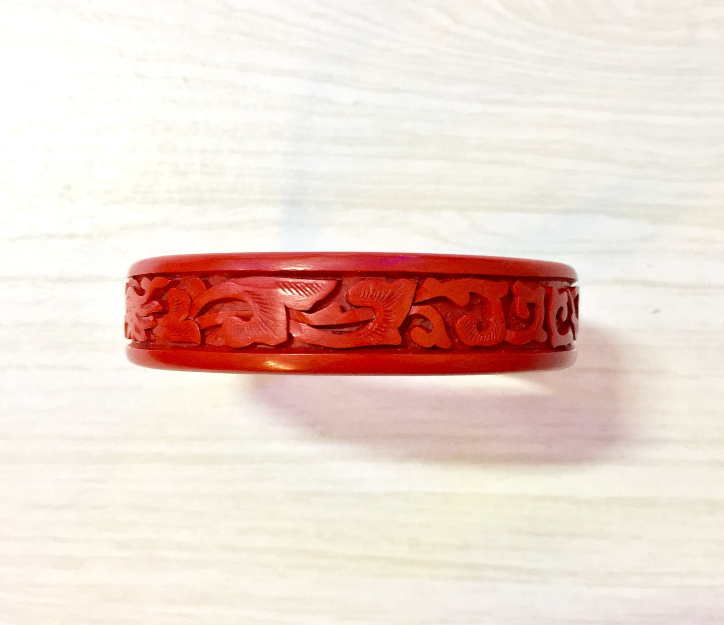 Carved red cinnabar bangle bracelet with intricate dragon design, vintage Asian jewelry piece