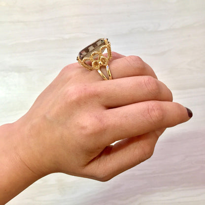 14K yellow gold smoky quartz cocktail ring with emerald cut stone on woman's hand