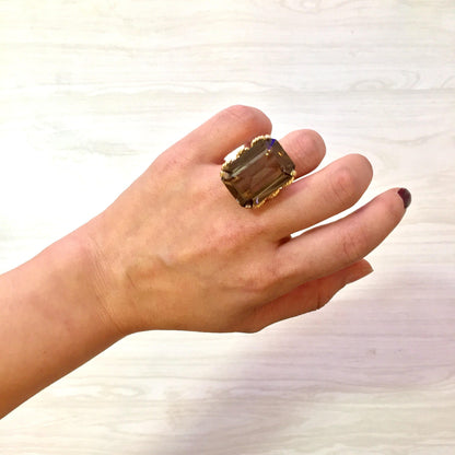 Vintage 14K yellow gold emerald-cut smoky quartz cocktail ring displayed on a hand against a light wood background.