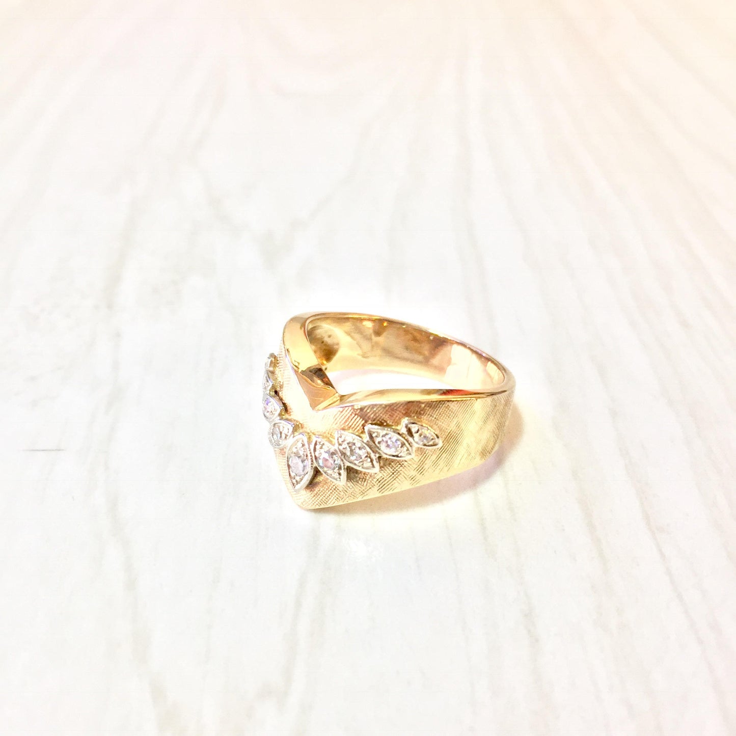 14 karat yellow gold chevron v-shaped diamond ring on white knit background