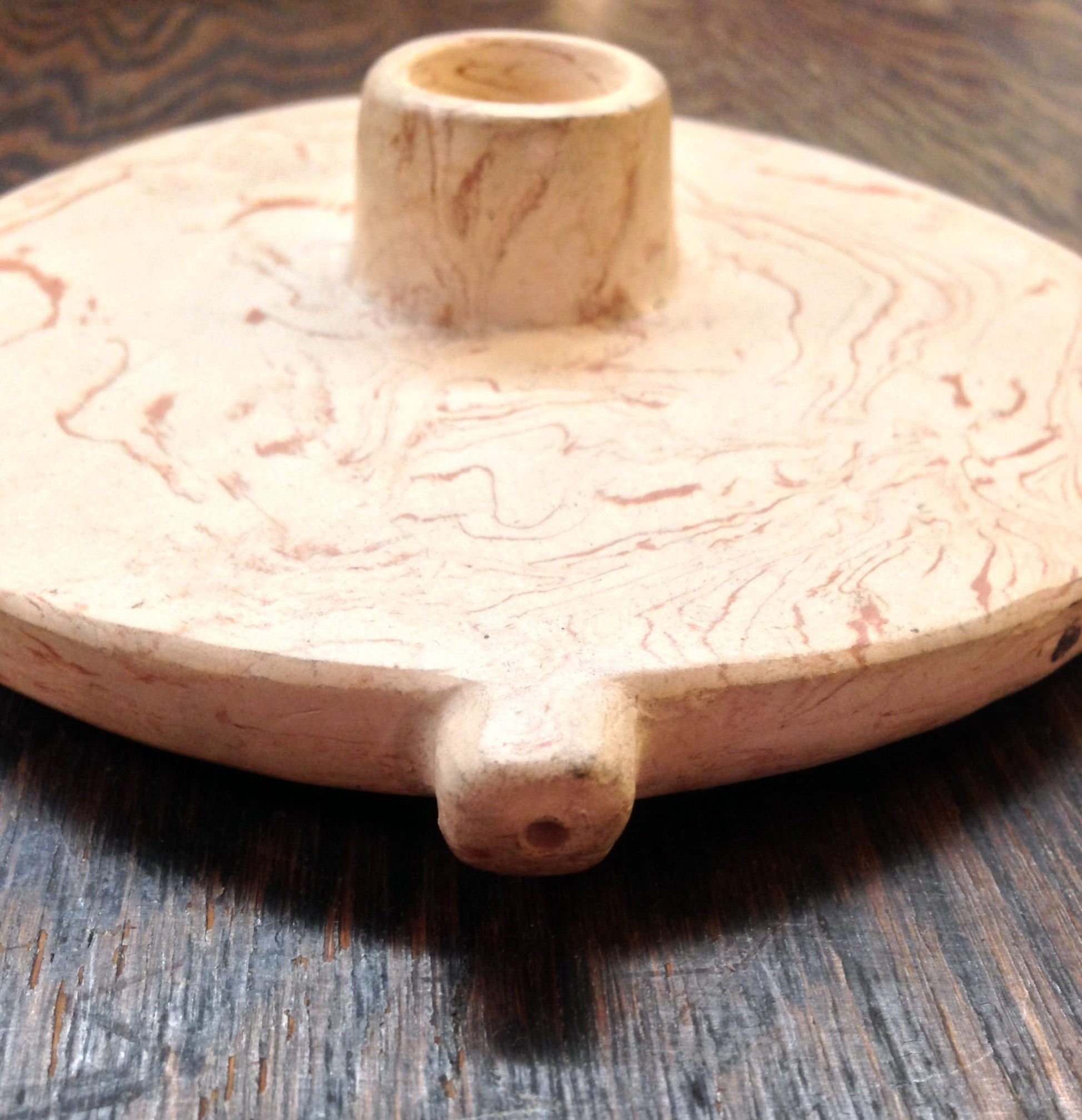 Antique double ceramic pipe on a wooden surface, featuring a marbled pink and white finish. The handcrafted tobacco pipe has two bowls connected to a single stem.