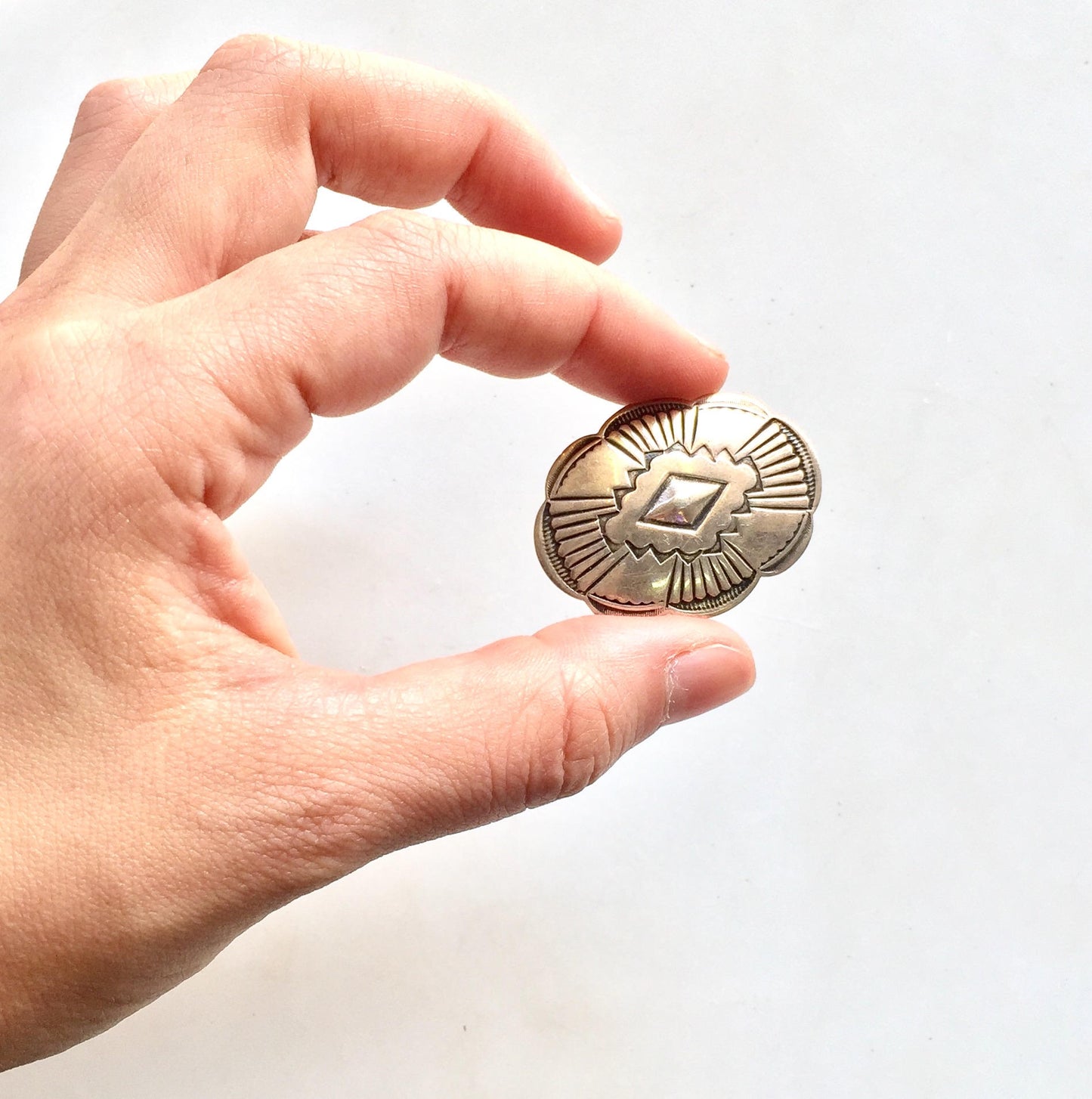 Sterling silver concho belt buckle clip held in hand, vintage southwestern style jewelry accessory for boho hippie fashion