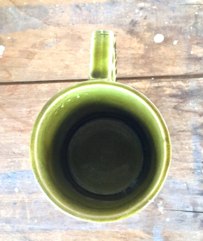 Vintage green Holt Howard ceramic mug on weathered wood surface, overhead view