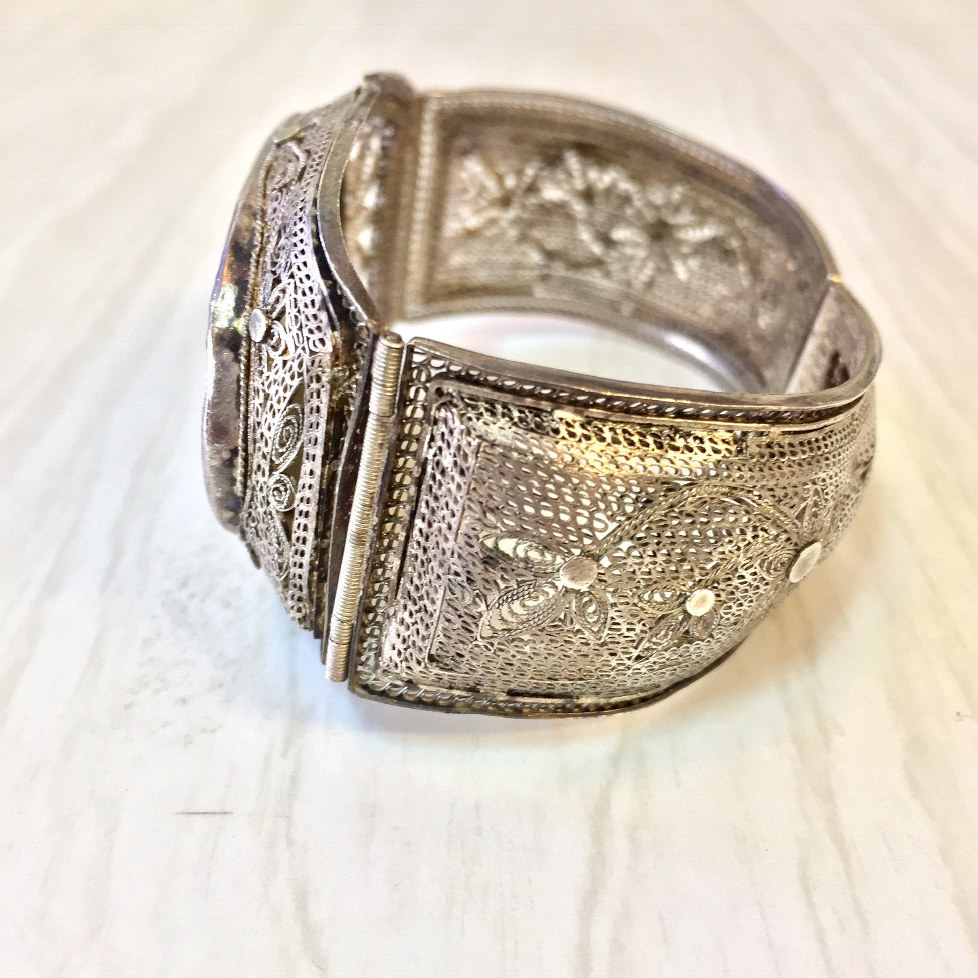 Antique sterling silver hinged filigree bracelet with intricately carved Asian-inspired designs on a horn or scrimshaw panel, displaying exquisite craftsmanship in a vintage piece of Asian jewelry.