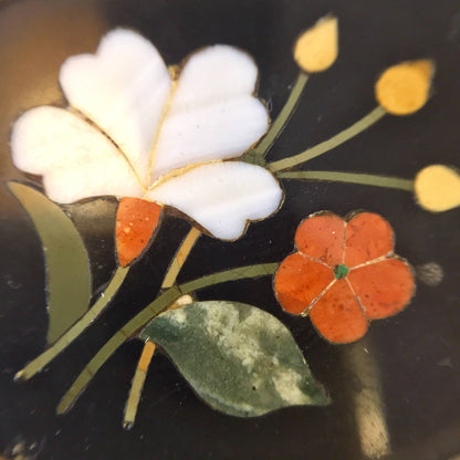 Vintage sterling silver floral brooch pin with inlaid natural stones featuring white flower petals and orange blossoms on a dark background.