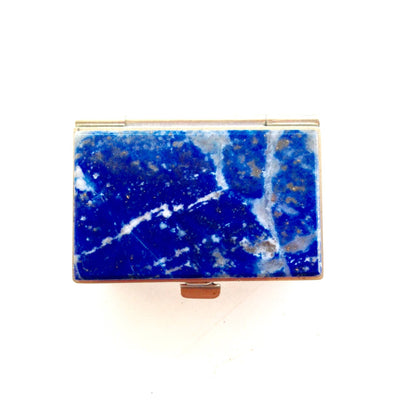 Blue lapis lazuli gemstone in a vintage gold-lined rectangular keepsake box, showing deep blue color with white calcite veining typical of lapis from Chile