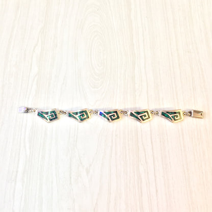 Vintage sterling silver link bracelet with inlaid green malachite gemstones on a wooden surface