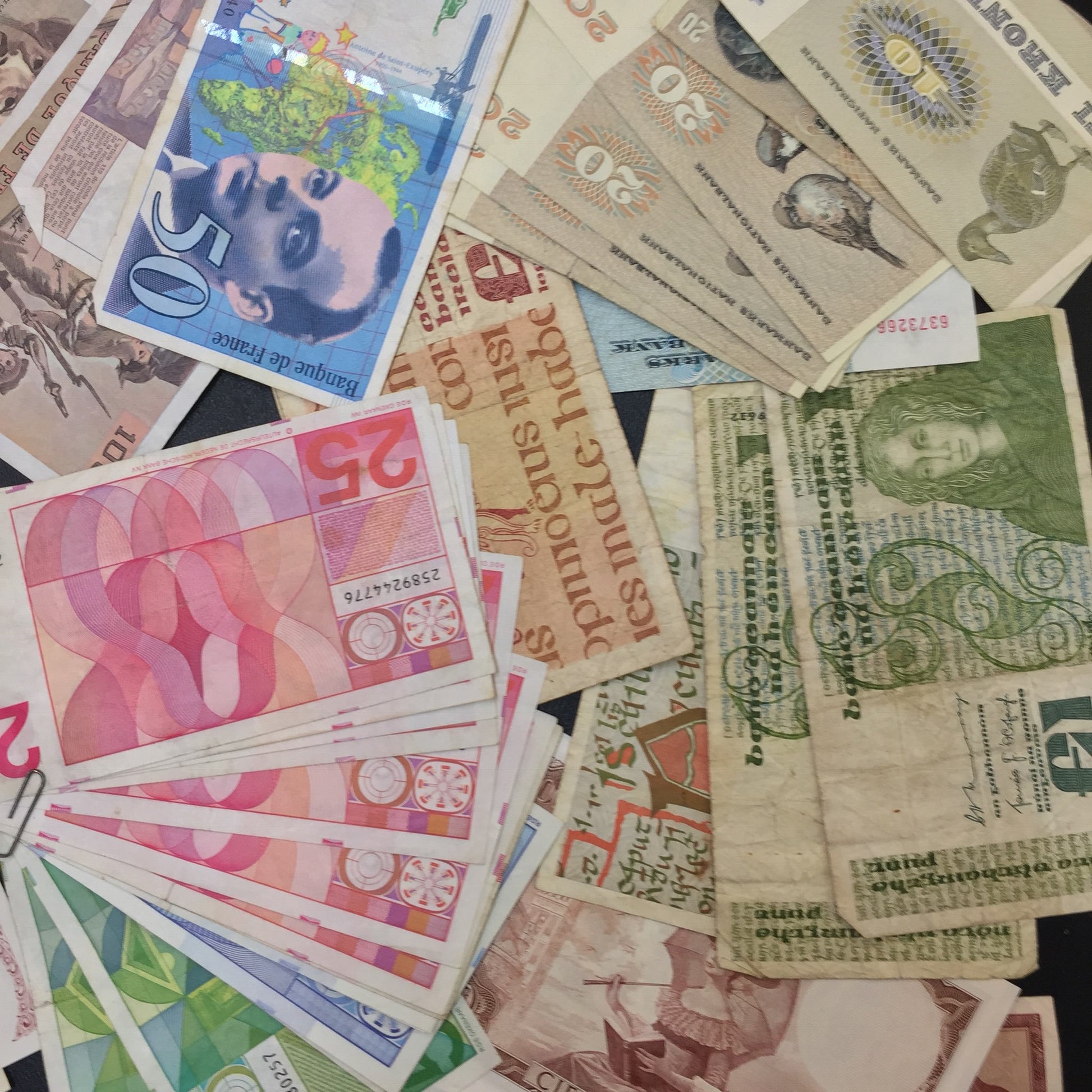 Vintage foreign currency banknotes from various countries, including Sweden, Africa and Poland, scattered on a flat surface, suitable for scrapbooking, crafting projects or collecting old international paper money.