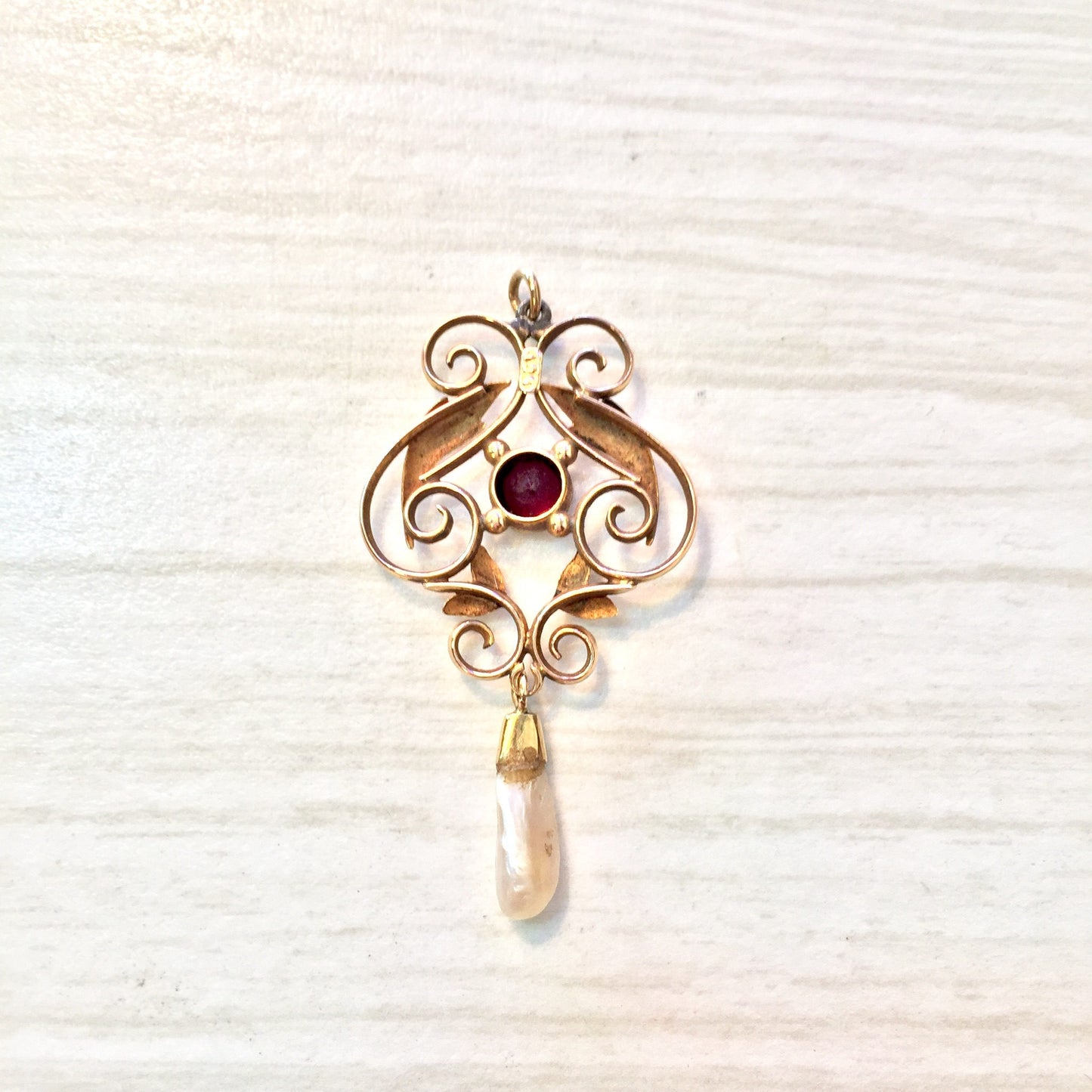 10 karat gold antique pendant featuring an intricate scrolling design accented with a dangling fresh water pearl and a vibrant purple amethyst gemstone against a textured white background.