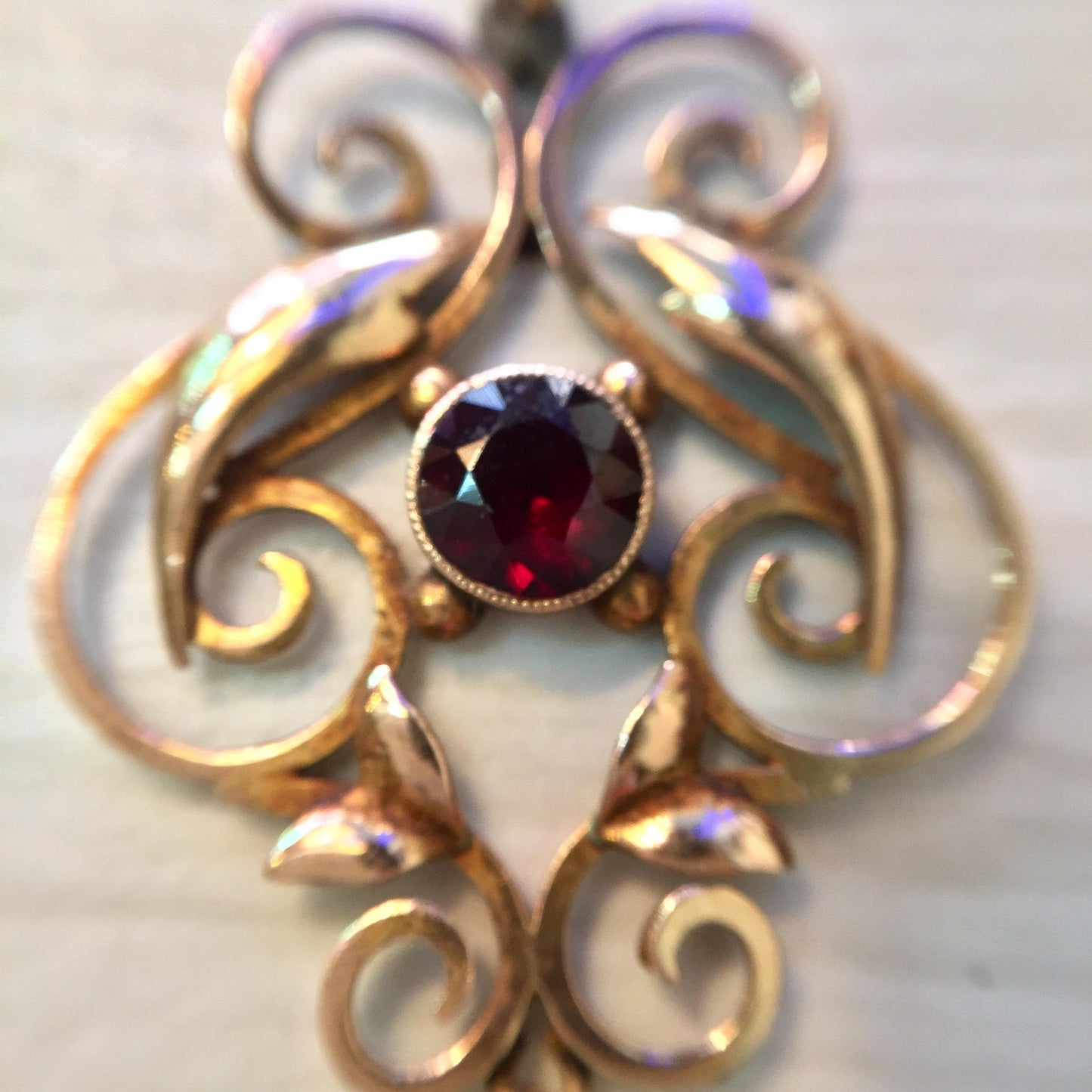 Antique 10K gold pendant featuring an intricate swirl design with a deep purple amethyst stone at the center and iridescent freshwater pearls accenting the ornate curves, creating an elegant and timeless piece of jewelry.