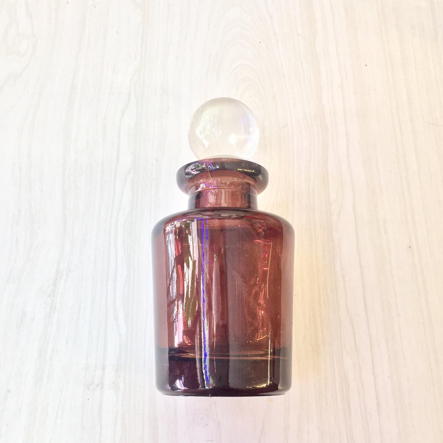 Vintage brown apothecary bottle with glass stopper on light wooden background