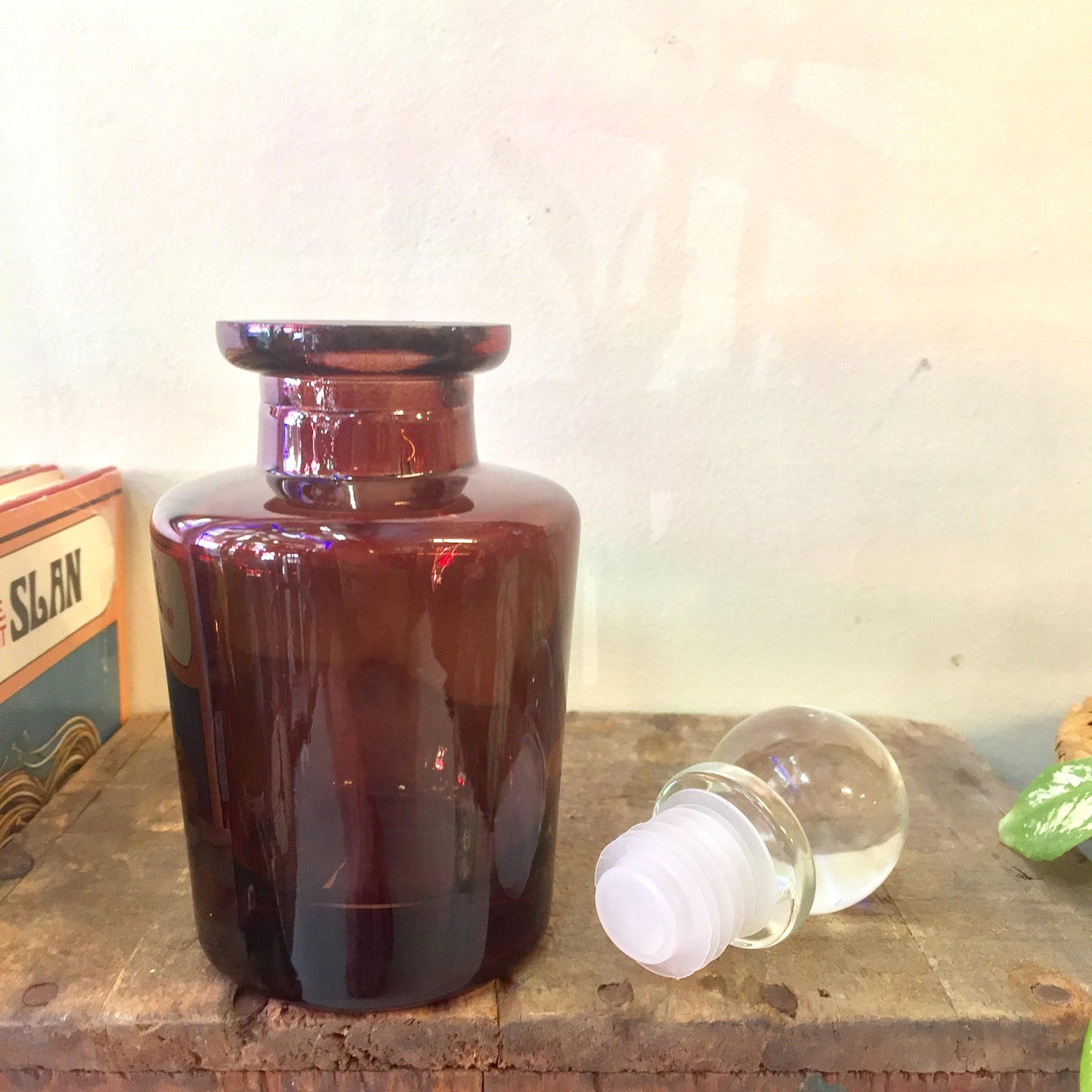 Vintage brown glass apothecary bottle with stopper on wooden surface, small amber glass jar for decor or storage.