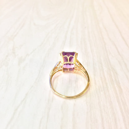 14 karat gold ring with an emerald cut amethyst gemstone, featuring intricate detailing on the band