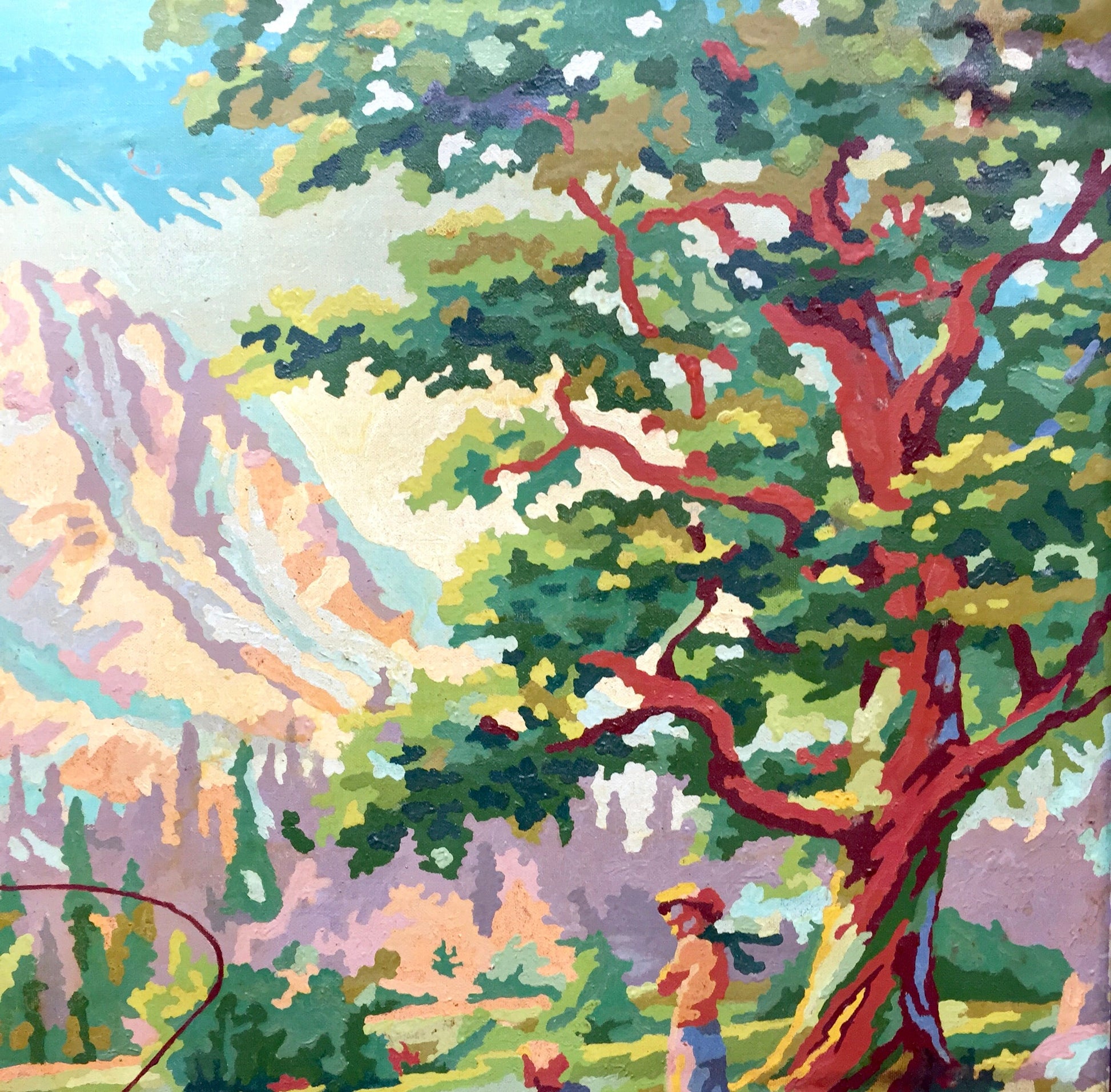 Colorful vintage paint by numbers landscape painting depicting a majestic tree with twisting red branches set against a backdrop of mountains, with two small figures fishing in the foreground, presented in a rustic wooden frame.