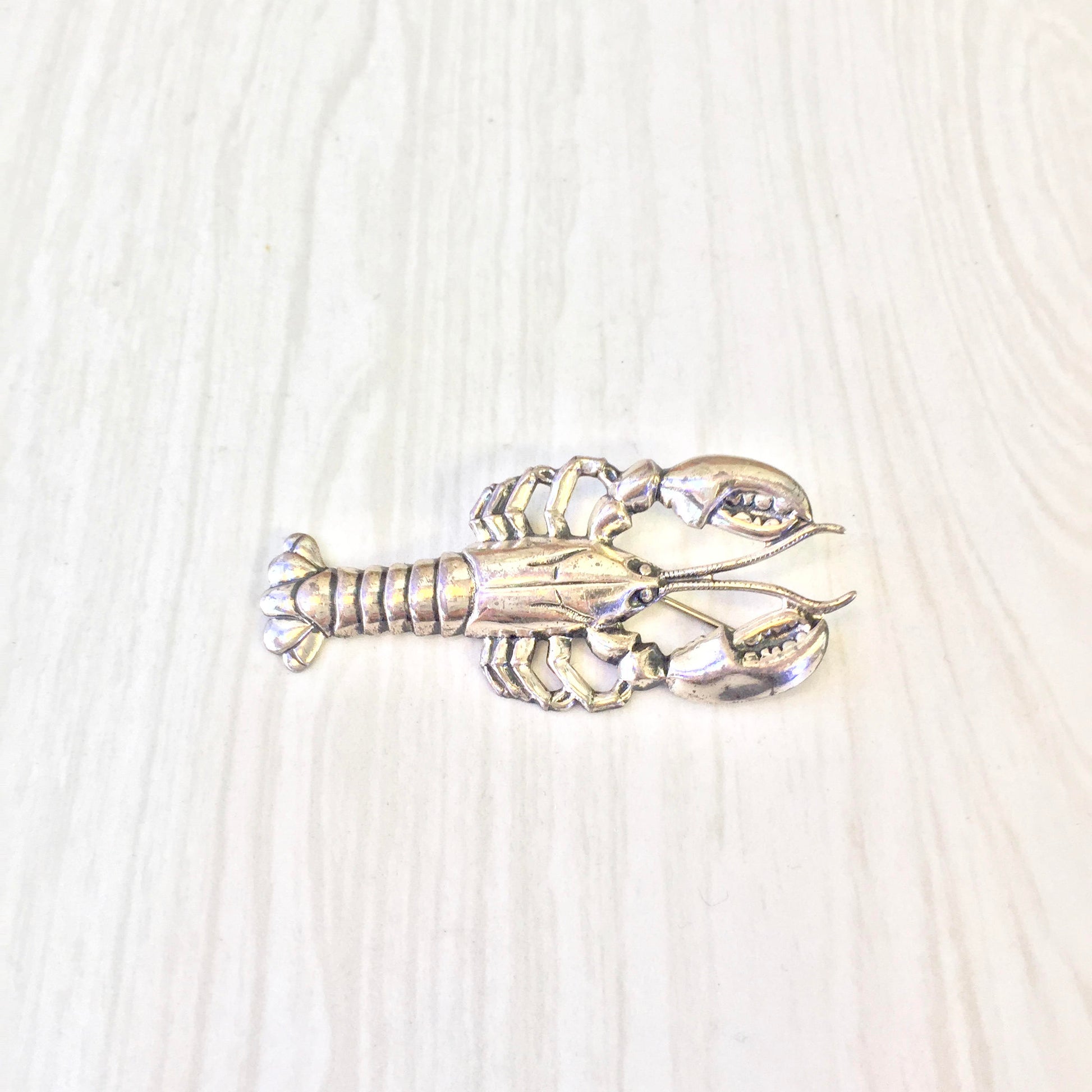 Vintage sterling silver lobster brooch pin on light wood background, detailed craftsmanship of crustacean shape, perfect holiday gift idea or unique addition to vintage jewelry collection