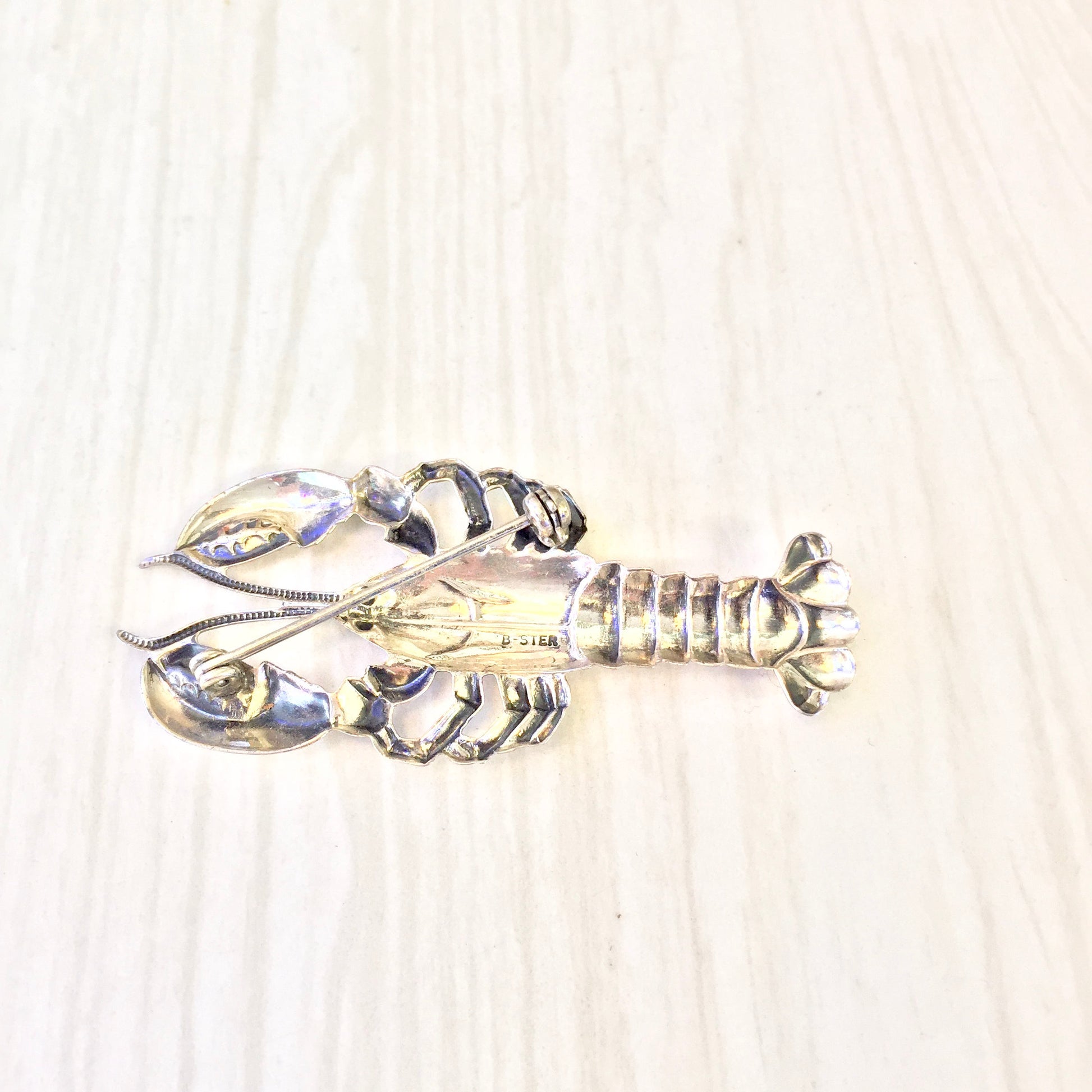 Vintage sterling silver lobster brooch pin, intricately designed crustacean jewelry piece with shiny metallic finish, perfect holiday or special occasion gift idea from vintage jewelry collection.