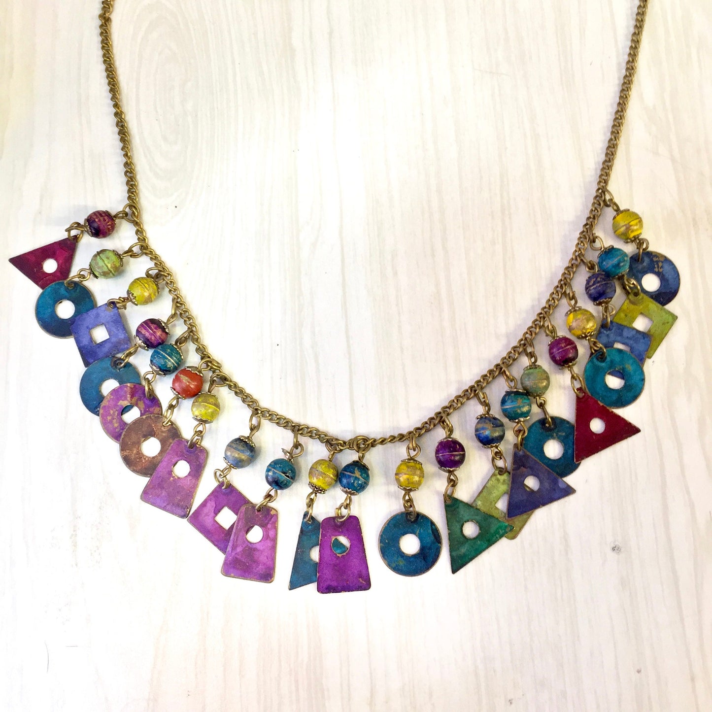 Vintage colorful beaded charm necklace with dangling geometric metal beads in various shapes and vibrant colors, making a unique statement piece and great holiday gift idea.