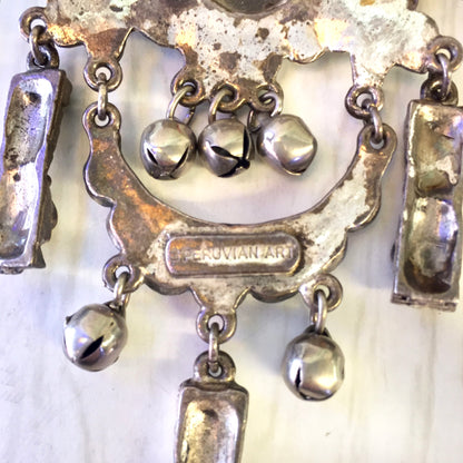 Vintage silver-tone Peruvian art brooch featuring dangling geometric shapes and bell-like charms, creating a unique statement jewelry piece that can be pinned as an eye-catching accessory or given as a gift.