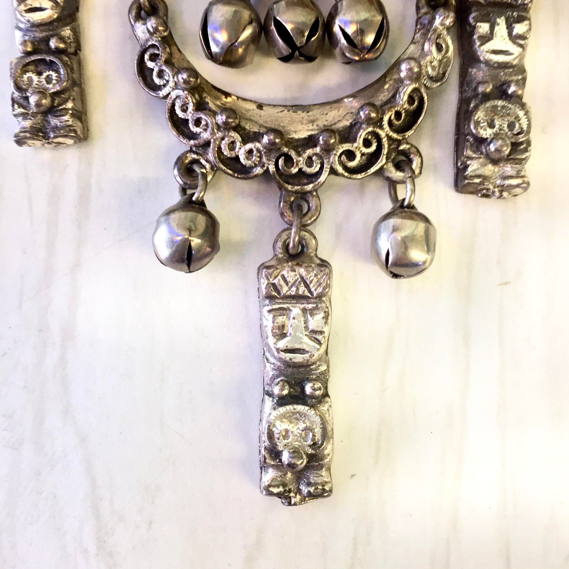 Vintage silver tone Peruvian art brooch with intricate metal design featuring ornate faces and dangling charms