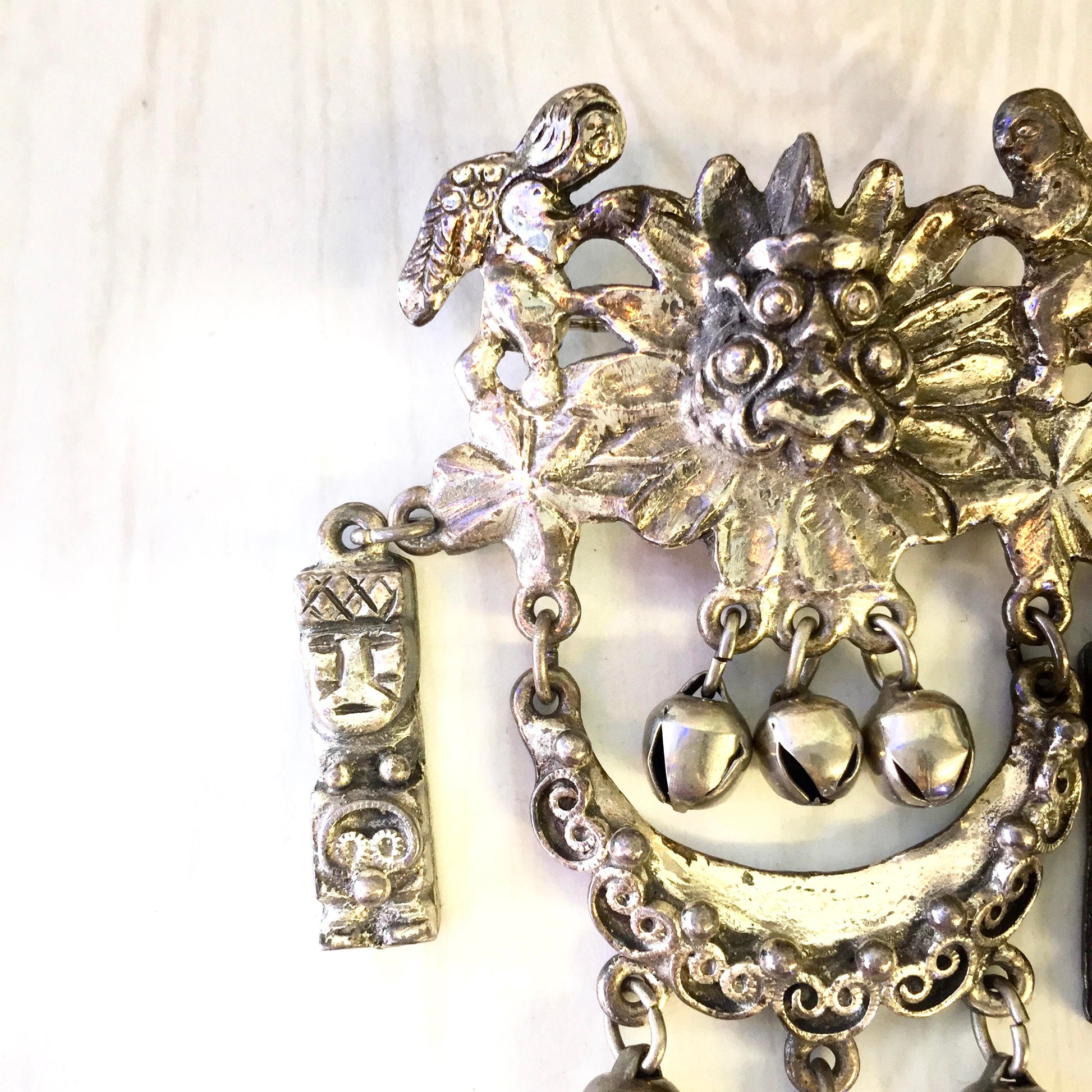 Vintage silver tone Peruvian art brooch featuring intricate floral and figurine designs with dangling accents, suitable as a statement jewelry piece or costume accessory.