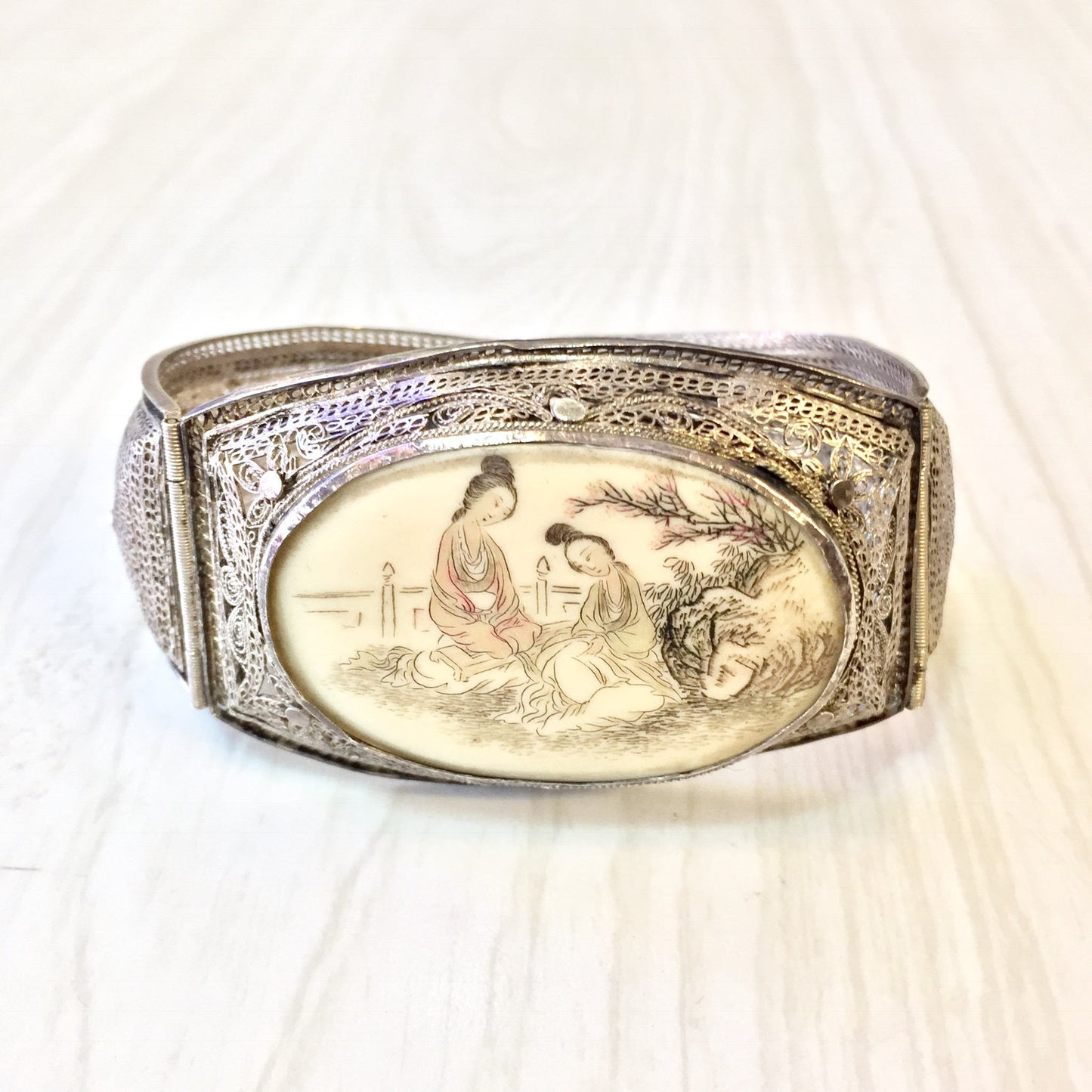 Antique sterling silver hinged bracelet featuring intricately carved Asian scene on horn or scrimshaw panel, showcasing detailed filigree metalwork in an elegant vintage Asian jewelry design.