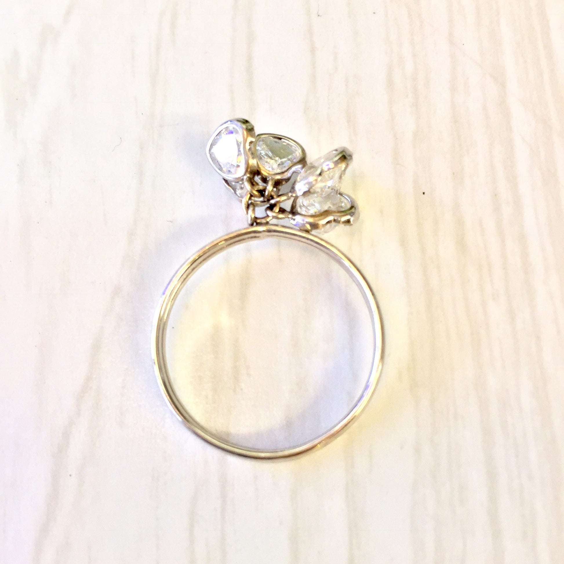 14 karat white gold ring with dangling heart charm adorned with sparkling cubic zirconia stones on a light wood background, perfect holiday gift idea for her.